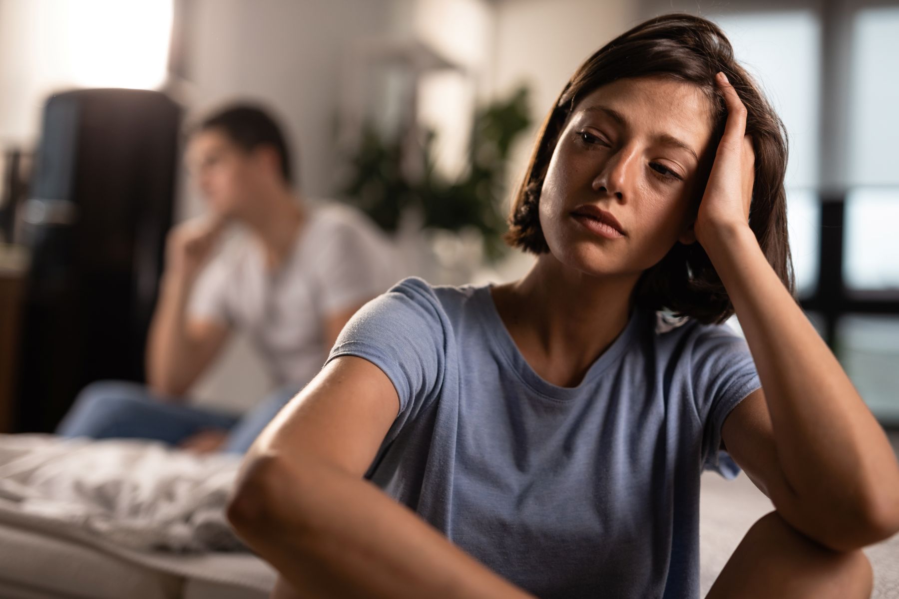 unhappy-woman-contemplating-after-argument-with-her-boyfriend-home-man-is-background